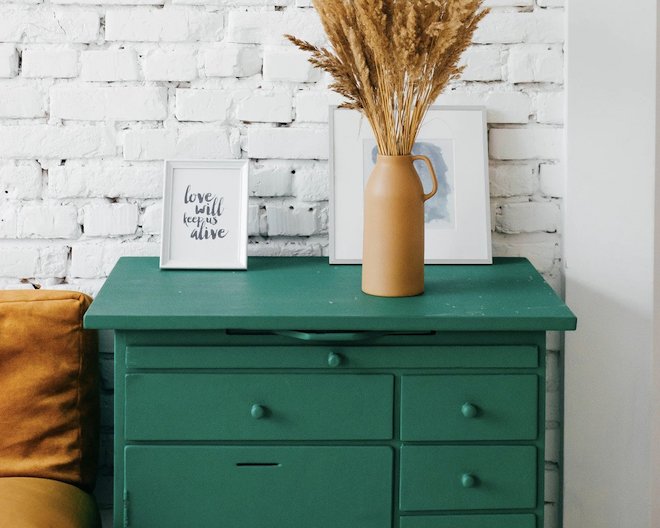 green desk with pictures and a flower on it